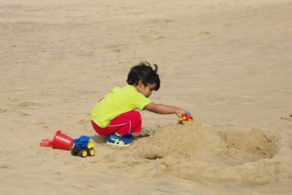 Little boy playing in the sand on a family beach vacation