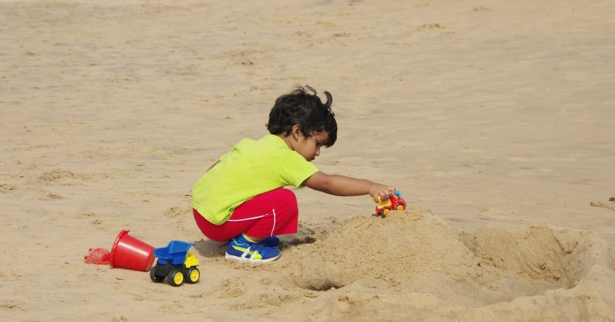 Little boy playing in the sand on a family beach vacation