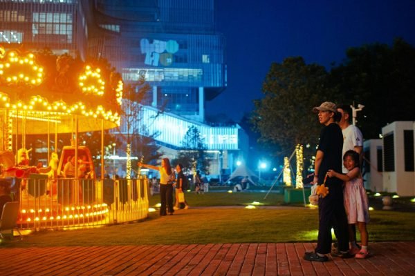 Families near a lit carousel at a theme park