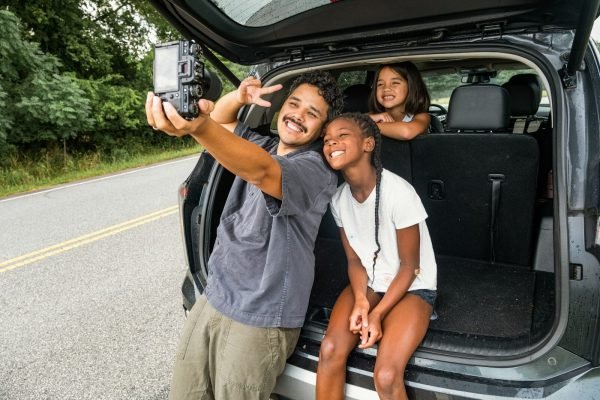 Father and daughters taking a selfie on a road trip