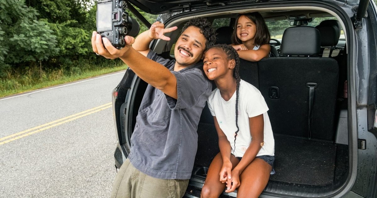 Father and daughters taking a selfie on a road trip